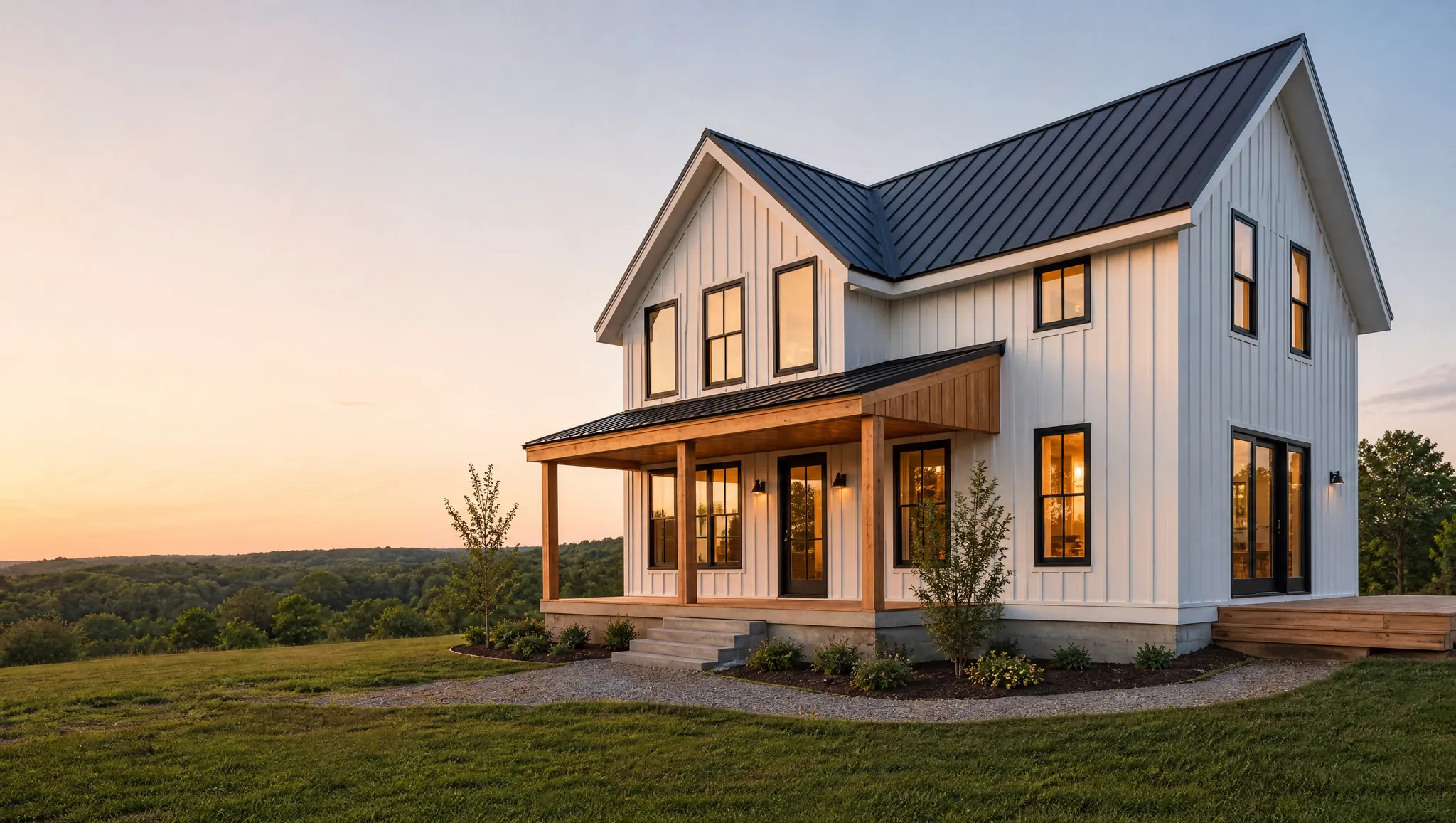New white farmhouse-style home with a dark metal roof, black windows and a cedar porch at sunset